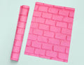 a piece of pink paper next to a pink brick wall