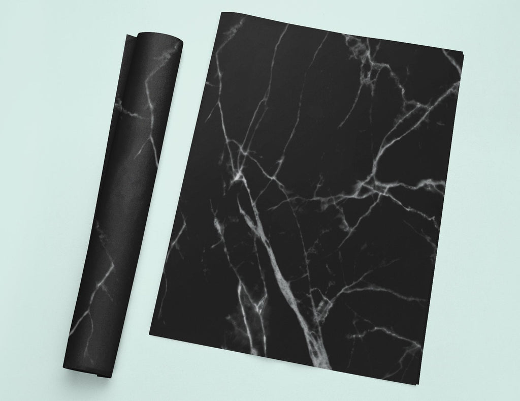 a piece of black marble next to a roll of black paper