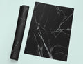 a piece of black marble next to a roll of black paper